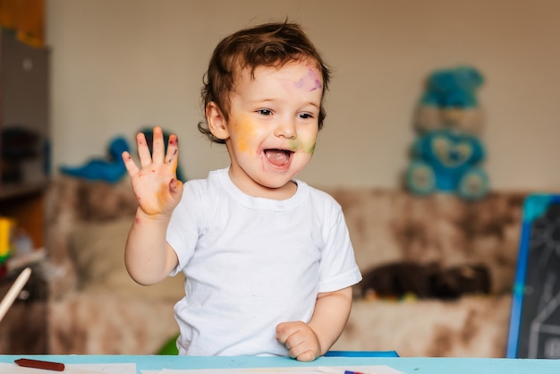 little boy plays with colorful markers on a piece of paper