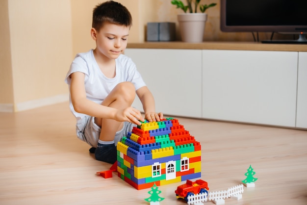 小さな男の子が建設キットで遊んで、家族全員のために大きな家を建てます。家族の家の建設。