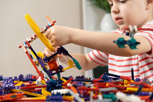 A little boy plays with a constructor creating figures from gears and sticks Development of logic and thinking in children