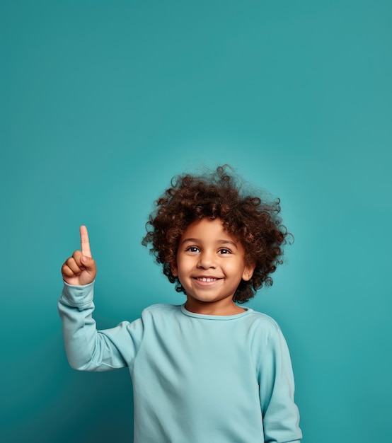 Photo little boy pointing upwards with minimalist blue background and copy space