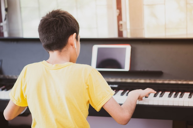 Little boy  practicing piano online digital tablet at home