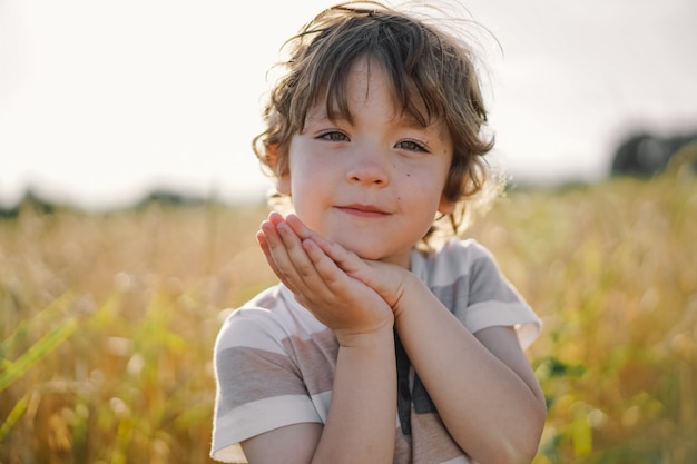 Little boy pregando in un campo di grano.