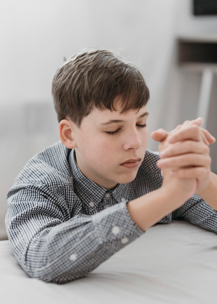 Photo little boy praying on his knees