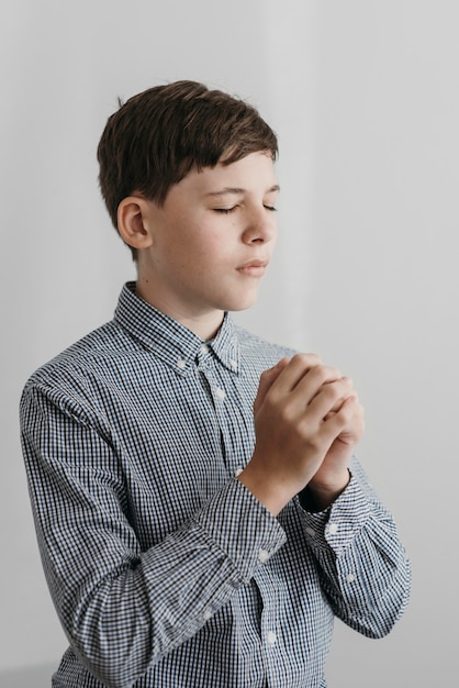 Photo little boy praying indoors