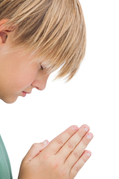 Little boy praying with eyes closed on white background 