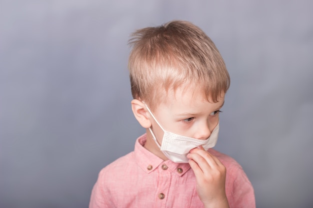 Little boy puts on a medical mask