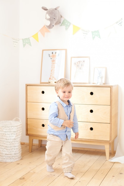 Un bambino mette i giocattoli in un cestino scandinavo per la camera dei bambini. decorazioni ecologiche per bambini. ritratto di un ragazzo che gioca all'asilo. cameretta e interior design. baby boy a casa.