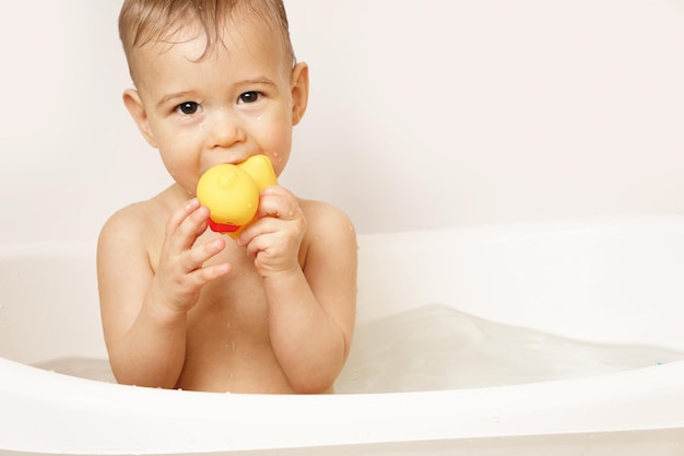 Little boy putting rubber duck in his mouth while taking a bath