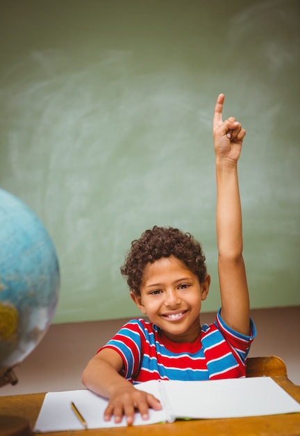 little boy raising hand in classroom