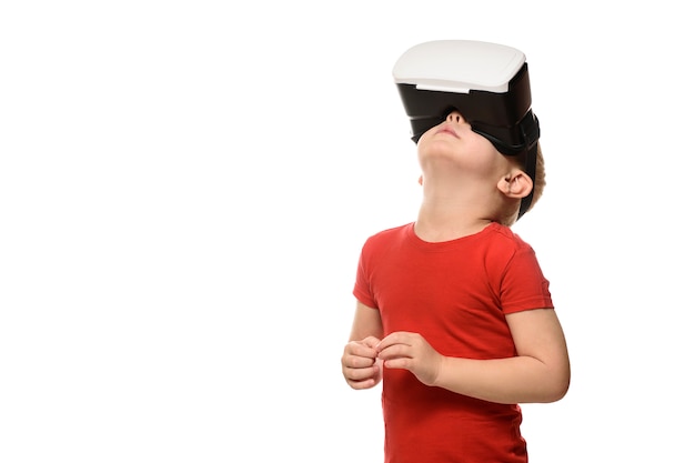 Маленький мальчик в красной рубашке испытывает виртуальную реальность, поднимая голову