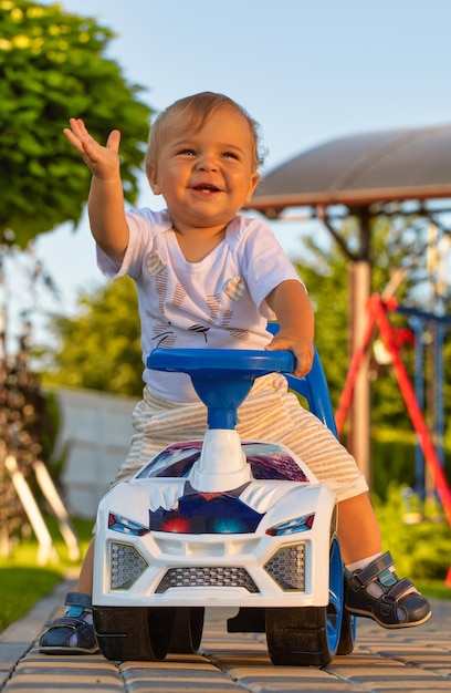 Un ragazzino guida un'auto della polizia giocattolo per bambini lungo una ricreazione in un vicolo del parco con un bambino all'aria aperta