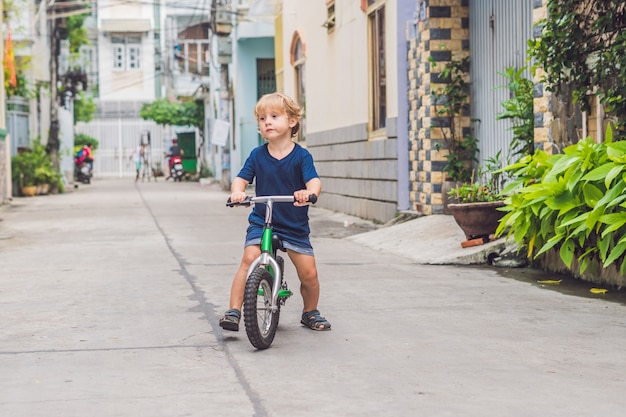 Photo little boy riding a bicycle on the street of the city