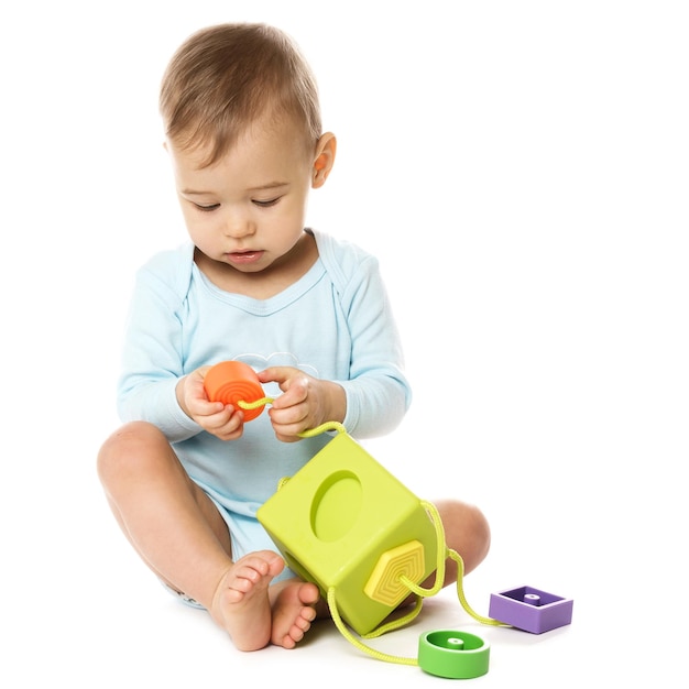 Little boy in romper sitting and playing with plastic toy
