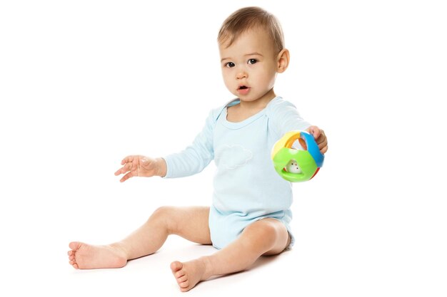 Little boy in romper sitting and playing with plastic toy