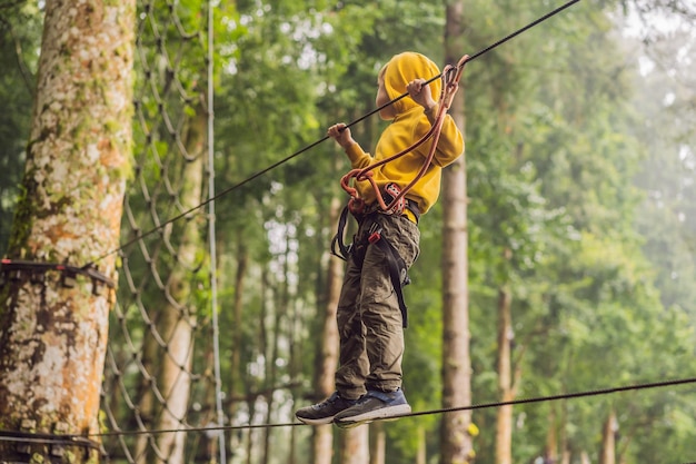 Little boy in a rope park active physical recreation of the\
child in the fresh air in the park training for children