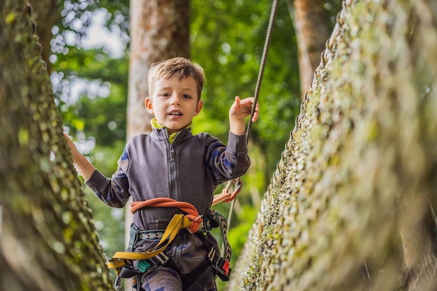 Photo little boy in a rope park active physical recreation of the child in the fresh air in the park training for children