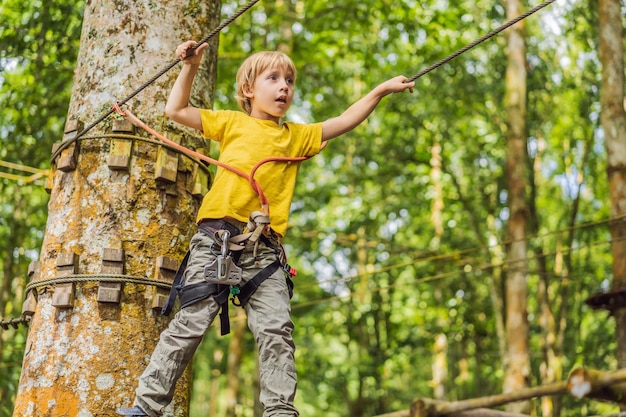 Little boy in a rope park active physical recreation of the\
child in the fresh air in the park training for children