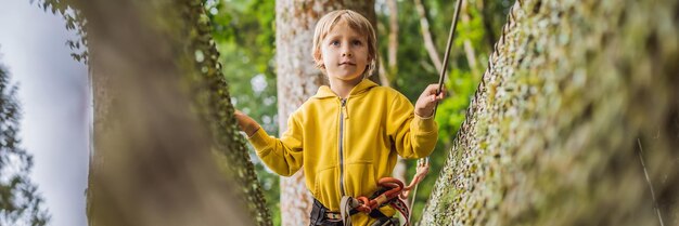 ロープパークの小さな男の子は、公園の新鮮な空気の中で子供のアクティブな物理的なレクリエーション