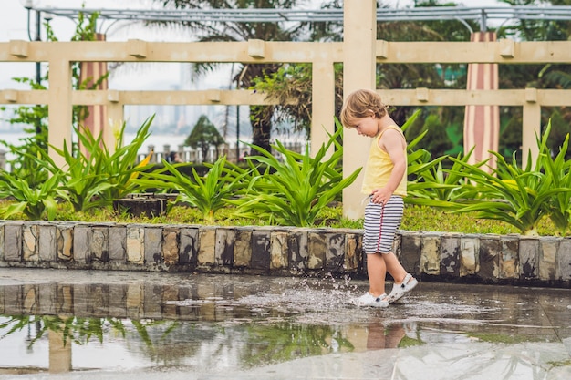 小さな男の子が水たまりを駆け抜けます。