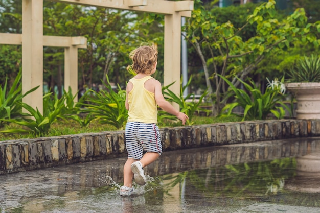 小さな男の子が水たまりを駆け抜ける