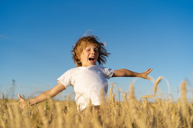 Photo little boy in rye field, runs and jumps happy baby, summer on a sunny day.