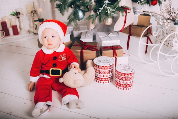 Little boy in Santa Claus costume in light interior