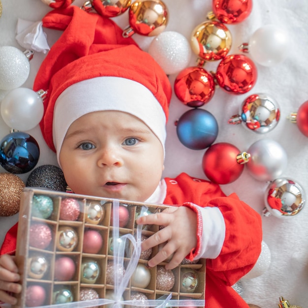 Маленький мальчик в костюме Санта-Клауса с рождественскими украшениями.