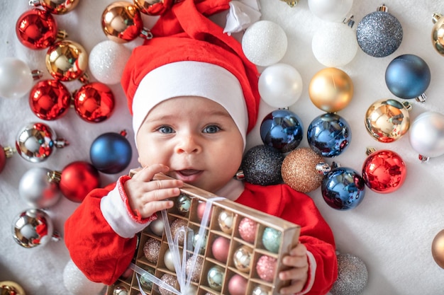 Little boy in a Santa Claus costume with Christmas decorations.