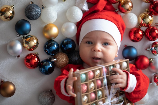 Little boy in a Santa Claus costume with Christmas decorations.