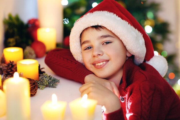 Little boy in Santa hat near fireplace in room