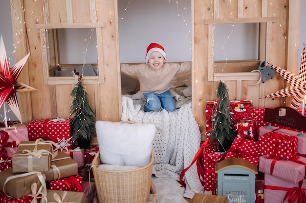 Little boy in santa hat playing in his chilndens room decorated room for christmas holidays