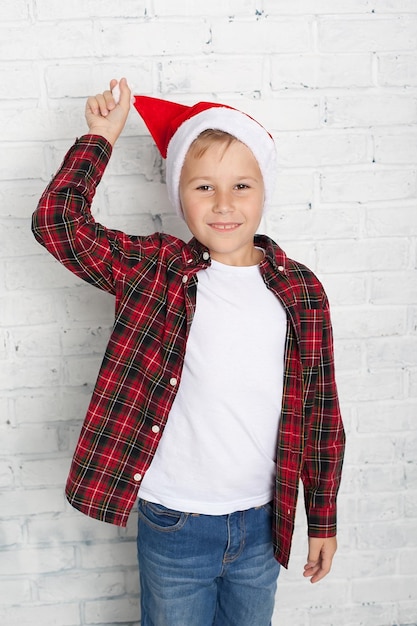 Ragazzino in santa cappello con casa di pan di zenzero su sfondo bianco carta di felice anno nuovo aspettando la vacanza