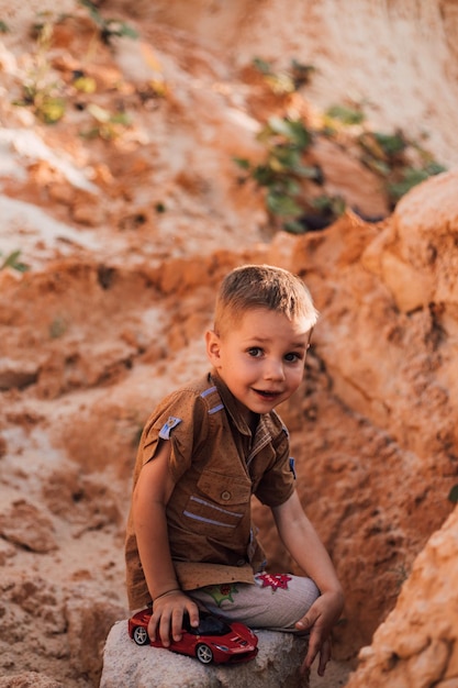 A little boy sat down on a rock among the sand