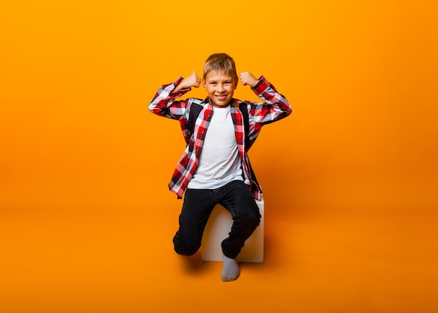 Photo little boy screams, writhes and shows class on yellow background