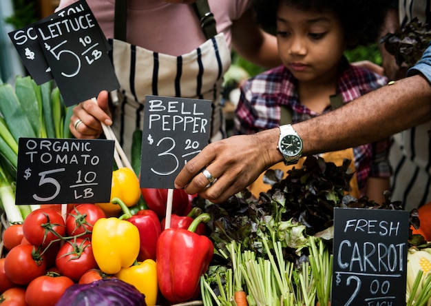 Photo little boy selling vegetable at market