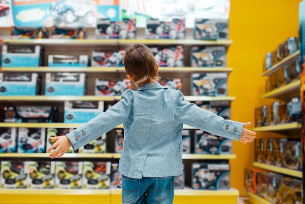Маленький мальчик на полке в детском магазине, вид сзади