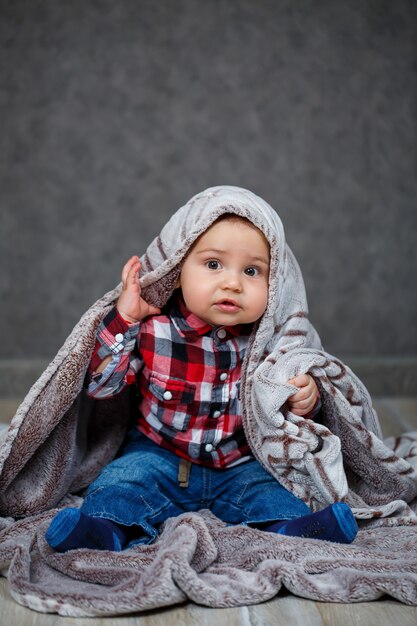 A little boy in a shirt is covered with plaid