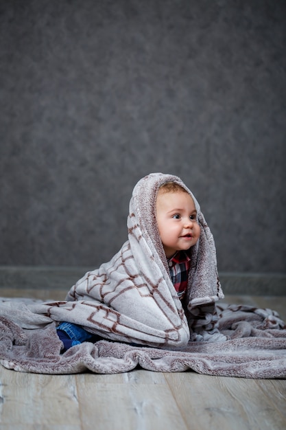 A little boy in a shirt is covered with plaid