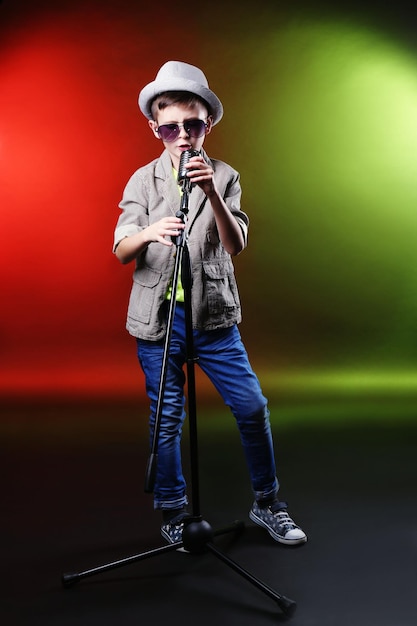 Little boy singing with microphone on a bright background