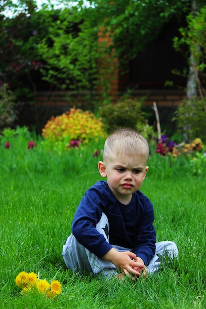 小さな男の子が草の上に座っています。セレクティブフォーカス