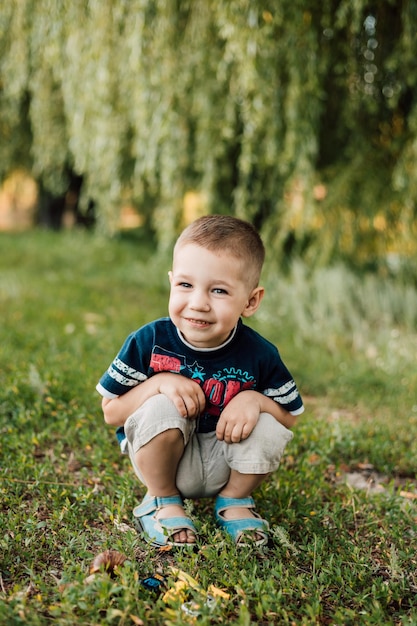 小さな男の子が草の中に座って、優しく微笑む