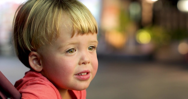 Photo little boy sits outside watches interest