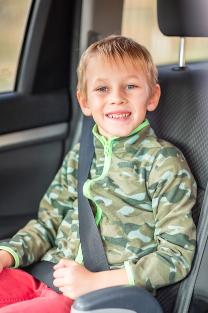 Little boy sitting on a booster seat buckled up in the car.\
children\'s car seat safety