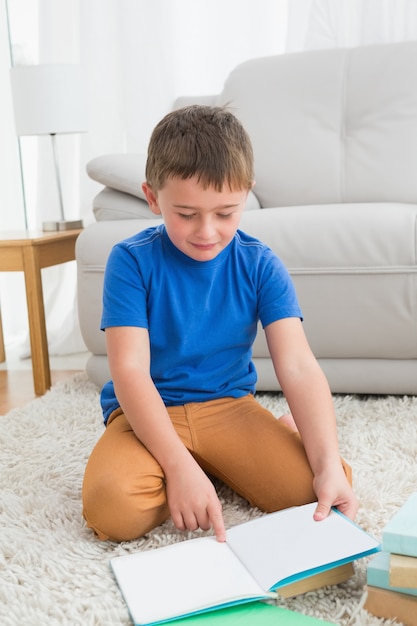 Ragazzino che si siede sul pavimento che legge libro di fiabe