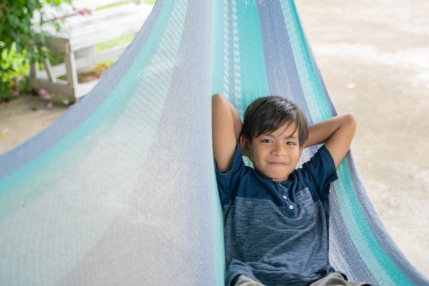 The little boy sitting at the hammock and he so happy