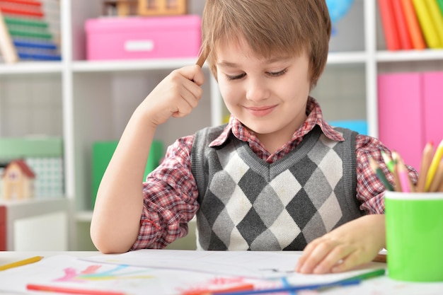 Little boy sitting at table and drawing with colorful pencils