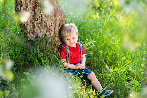 Little boy sitting under a tree and resting