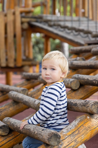 Little boy sitting between wood logs on playground