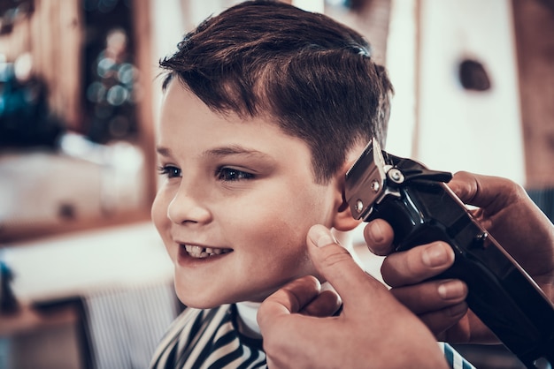 The little boy smiles when his hair is cut.