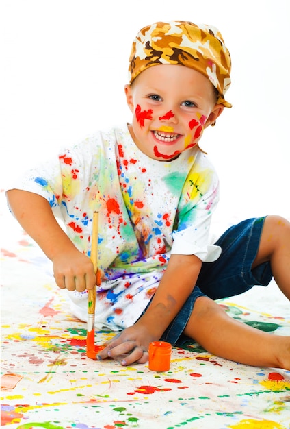 Little boy stained in paint draws